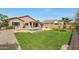 Spacious backyard featuring a swimming pool, lush lawn, desert landscaping, and covered patio at 18051 W Port Royale Ln, Surprise, AZ 85388