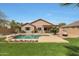 Backyard featuring a sparkling pool, desert landscaping, lush lawn, and an outdoor kitchen at 18051 W Port Royale Ln, Surprise, AZ 85388