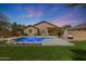 Lush backyard showcasing a sparkling pool, a cozy fire pit, and a manicured lawn at 18051 W Port Royale Ln, Surprise, AZ 85388