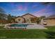 Backyard oasis featuring a private pool, green lawn, a covered patio and firepit perfect for outdoor entertaining at 18051 W Port Royale Ln, Surprise, AZ 85388
