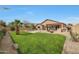 Expansive backyard featuring a green lawn, pool, outdoor kitchen, and desert landscaping at 18051 W Port Royale Ln, Surprise, AZ 85388