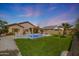 Lush backyard with a pool, grass, and privacy landscaping at 18051 W Port Royale Ln, Surprise, AZ 85388