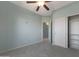 Bedroom with plush carpet, closet and ceiling fan; bathed in soft, natural light at 18051 W Port Royale Ln, Surprise, AZ 85388