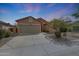 Single-story home featuring a two-car garage, desert landscaping, and a long driveway at 18051 W Port Royale Ln, Surprise, AZ 85388