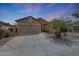 Single-story home featuring a two-car garage, desert landscaping, and a long driveway at 18051 W Port Royale Ln, Surprise, AZ 85388
