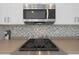 Up close, a sleek stovetop and tile backsplash complement the stainless steel microwave and cabinets at 18051 W Port Royale Ln, Surprise, AZ 85388