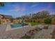 Inviting backyard pool with basketball hoop, lush lawn, and decorative planters at 18051 W Port Royale Ln, Surprise, AZ 85388