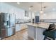 The modern kitchen features white cabinets, an island with seating, stainless steel appliances, and pendant lighting at 18159 W Piro St, Goodyear, AZ 85338