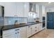 Modern kitchen with white cabinets, stainless steel appliances, gray countertops, and wood-look tile flooring at 18159 W Piro St, Goodyear, AZ 85338