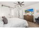Bedroom with a large bed, ceiling fan, TV, and an en-suite bathroom visible through sliding door at 18956 W Laurel Ln, Surprise, AZ 85388