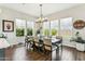 Bright dining room with dark wood floors, an elegant chandelier, and beautiful backyard views at 22743 N 97Th Dr, Peoria, AZ 85383