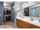 Bathroom featuring double sinks, cabinets, large mirror and walk-in closet at 23945 N Pablo N Ct, Sun City, AZ 85373