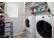Functional laundry room with modern washer and dryer, storage shelves, and shoe rack at 23945 N Pablo N Ct, Sun City, AZ 85373