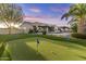 This backyard boasts a putting green, pool, patio, and lush landscaping, ideal for entertainment at 24695 S 195Th Way, Queen Creek, AZ 85142