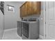 Laundry room with stainless steel washer and dryer, wooden cabinets and tile floor at 24695 S 195Th Way, Queen Creek, AZ 85142