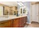 Bathroom featuring double sinks, wood cabinets, framed mirrors, and a glass enclosed walk-in shower at 25862 N 108Th Ave, Peoria, AZ 85383