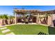 Cozy outdoor patio featuring a pergola, artificial grass, and desert landscaping at 25862 N 108Th Ave, Peoria, AZ 85383