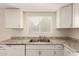 Close-up of white kitchen sink and countertop with white cabinets above and below at 27 W Concorda Dr # 104, Tempe, AZ 85282