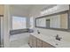 Bright bathroom features dual sinks, soaking tub, large window, and gray countertops in a modern style at 2806 E Pontiac Dr, Phoenix, AZ 85050