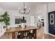 Stylish dining area with a modern chandelier, wood table, and a glimpse of the kitchen at 30433 W Bellview St, Buckeye, AZ 85396