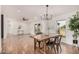 This dining room features wood floors, white walls, natural light, and an industrial chandelier at 30433 W Bellview St, Buckeye, AZ 85396