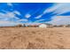 Expansive property showcasing a large, open lot with multiple outbuildings under a partly cloudy sky at 30433 W Bellview St, Buckeye, AZ 85396