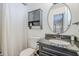 Classic bathroom with a dark vanity, a toilet, a cabinet, hardwood floors, and a round mirror at 3246 E Palm Ln, Phoenix, AZ 85008