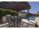 Outdoor dining area with built-in grill and a pool with a water feature, perfect for entertaining and relaxation at 3429 E Constance Way, Phoenix, AZ 85042