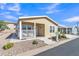 Inviting tan home with cozy front porch and desert landscaping providing both charm and low water needs at 40511 N Birdie St, San Tan Valley, AZ 85140