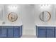 Dual sink bathroom featuring navy blue vanities, brushed gold fixtures, and round mirrors with contemporary decor at 4247 S Zenith --, Mesa, AZ 85212
