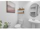 Modern powder room featuring white walls, floating shelves, a round mirror, and a stylish pedestal sink at 4247 S Zenith --, Mesa, AZ 85212
