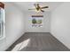 Bright bedroom with neutral carpet, ceiling fan, and a large window at 44271 W Oster Dr, Maricopa, AZ 85138