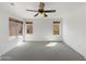 Bright bedroom with neutral carpet, ceiling fan, and dual windows letting in natural light at 44271 W Oster Dr, Maricopa, AZ 85138