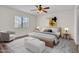 This is a stylishly furnished bedroom featuring a plush bed, chair, ceiling fan, and an abundance of natural light at 7952 W Oregon Ave, Glendale, AZ 85303