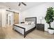 Serene bedroom with a modern bed, light hardwood floors, and a sliding barn door to the ensuite bathroom at 7955 E Chaparral Rd # 116, Scottsdale, AZ 85250