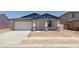 Inviting single-story home with a two car garage, stone accents, and sidewalk at 15154 W Gray Fox Trl, Surprise, AZ 85387