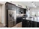 Modern kitchen featuring stainless steel appliances, sleek black cabinetry, and a stylish island with a marble countertop at 34949 N Donald Way, San Tan Valley, AZ 85140