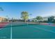 A community tennis court boasts a pristine green surface, netted boundaries, and well-maintained surroundings under a clear sky at 4741 W Annette Cir, Glendale, AZ 85308