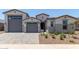 New construction home featuring a three car garage with modern elevation and desert landscaping at 23724 N 165Th Dr, Surprise, AZ 85387