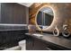 Modern powder room with a vessel sink, round mirror, dark vanity and beautiful decorative lighting at 4316 N 86Th Pl, Scottsdale, AZ 85251