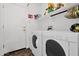 A laundry room features a white washer and dryer set with overhead shelving and storage for detergents and cleaning supplies at 5424 S 15Th St, Phoenix, AZ 85040