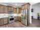 Well-lit kitchen with stainless steel appliances, custom cabinets, stone backsplash, and wood-look floors at 8246 W Melinda Ln, Peoria, AZ 85382
