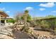 Beautifully landscaped backyard with outdoor kitchen, fire pit, and serene seating area for relaxation and entertaining at 7723 E Visao Dr, Scottsdale, AZ 85266