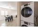 Modern white stacked laundry units with a glimpse of the dining area featuring tile flooring at 10828 N Biltmore Dr # 113, Phoenix, AZ 85029