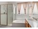 Bright bathroom featuring a glass-enclosed shower, tub, and a stylish vanity with white countertops at 12841 N 19Th St, Phoenix, AZ 85022