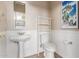 Cozy bathroom features pedestal sink, toilet, shelving, and a decorative mirror at 12841 N 19Th St, Phoenix, AZ 85022