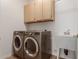 Well-equipped laundry room with washer, dryer, utility sink, and storage cabinets at 12841 N 19Th St, Phoenix, AZ 85022