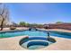 Backyard pool with spa features a rock waterfall, lush landscaping, and a basketball hoop at 1289 E Palo Blanco Way, Gilbert, AZ 85296