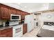 Functional kitchen featuring wood cabinets, white appliances, and tiled flooring for easy maintenance at 13630 W Aleppo Dr, Sun City West, AZ 85375