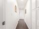 Well-lit hallway with dark wood flooring and framed artwork adorning the white walls at 14374 W Amelia Ave, Goodyear, AZ 85395
